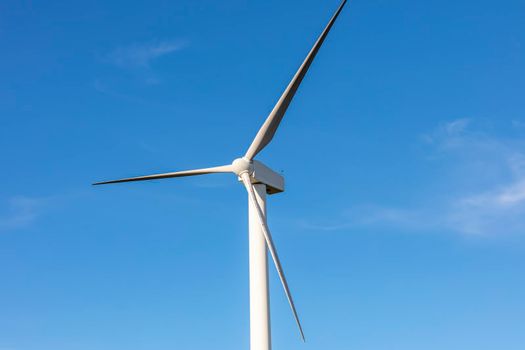 A large three blade industrial wind turbine generating electricity in a wind farm