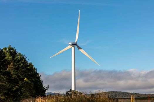 A large three blade industrial wind turbine generating electricity in a wind farm