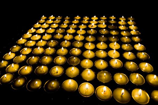 Ritual candles in wide candlesticks on a black background. Tibetan monastery.