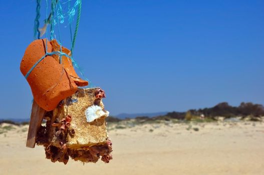 Abstract sculpture or totem made of stone, crocks and seashells in the ocean shore, summer, Tavira, Portugal