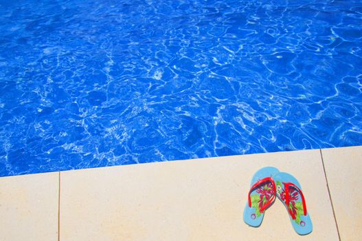 Blue summer shoes near the swimming pool with blue clear water, Spain