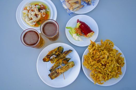 Two beers, white plates with different snacks, summer