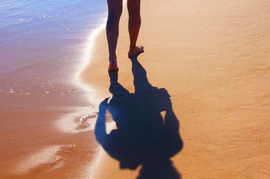 Man and his shadow walking alone on the seashore, summer, Portugal