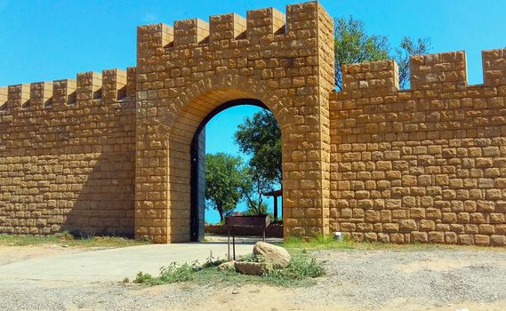 Old castle wall with arc and olive trees inside, summer, Azerbaijan
