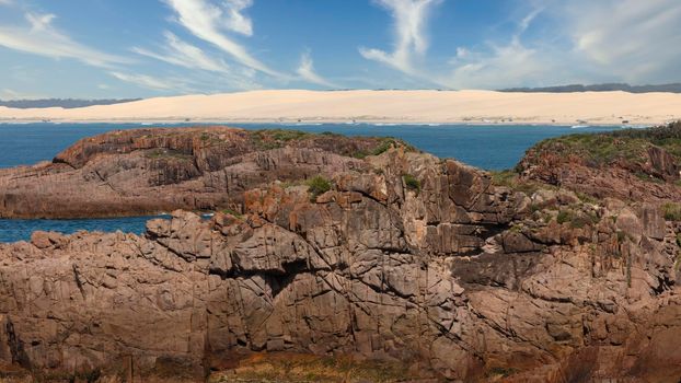 The brown Rocks in front of the Stockton Sand Dunes and blue water of the Tasman Sea at Birubi Point near Port Stephens in regional New South Wales in Australia