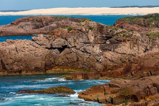 The brown Rocks in front of the Stockton Sand Dunes and blue water of the Tasman Sea at Birubi Point near Port Stephens in regional New South Wales in Australia