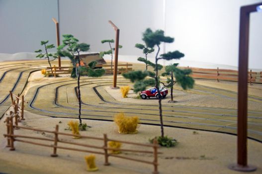 Small toy house, red car, trees and lantern in toy track