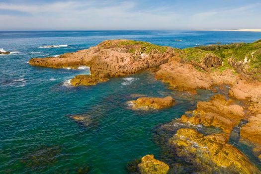 Aerial view of the brown Rocks and blue water of the Tasman Sea at Birubi Point near Port Stephens in regional New South Wales in Australia