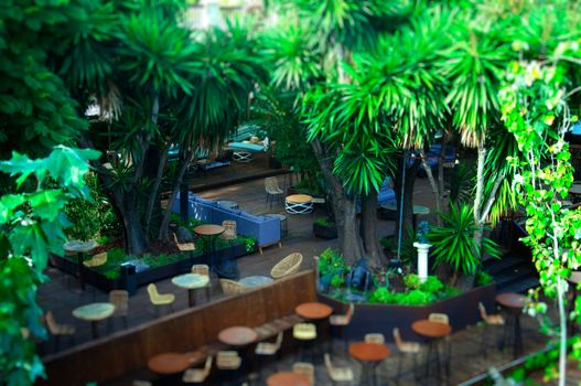 View of outdoor restaurant with green trees, tilt effect, summer