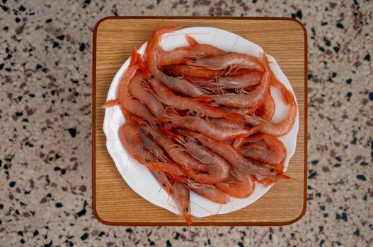 White plate full of shrimps, on the chair, milticolored background