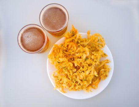 Fried yellow fritters with small shrimps and two beers, isolated