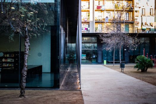 The Biblioteca Sant Antoni - Joan Oliver in the Sant Antoni district in Barcelona: side shot of south est corner of building. Inside courtyard with the playground for children and the large windows of the library.