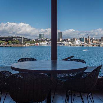 Marina Port Vell in Barcelona (Catalonia, Spain) as seen from a restaurant near the Terminal North. Active men rowing alone in the inland waters at the harbor. Yachts moored in the dock a short walk from the city centre.