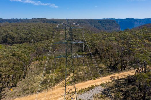 Aerial view of transmission towers and power lines running through a forest in regional Australia