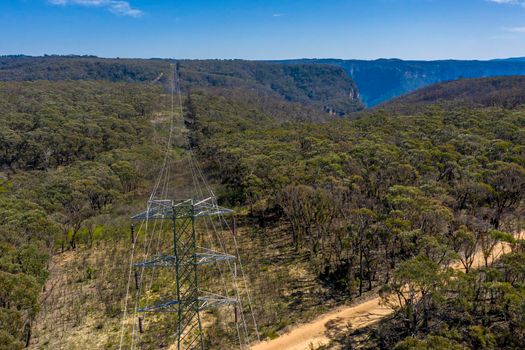 Aerial view of transmission towers and power lines running through a forest in regional Australia