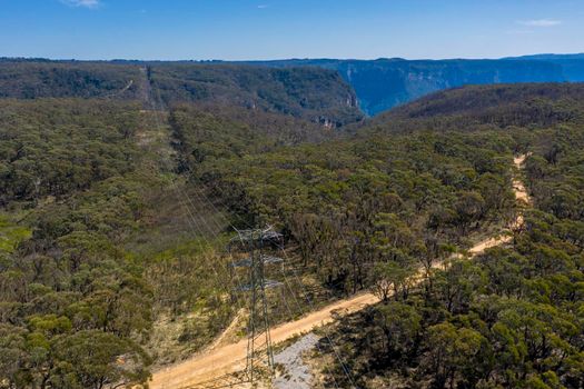 Aerial view of transmission towers and power lines running through a forest in regional Australia