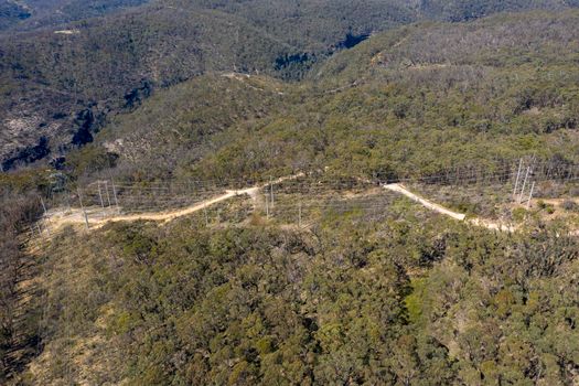 Aerial view of transmission towers and power lines running through a forest in regional Australia