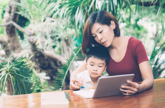 Son using digital tablet computer for study and learn to internet online with mother together, education from home, family recreation, mom teach boy and homework with technology, lifestyle concept.