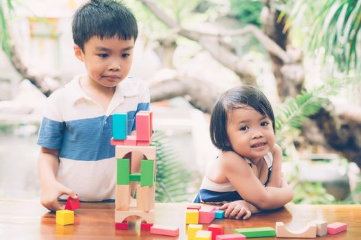 Asian boy and gril playing wooden block toy on table for creative and development with enjoy, happy child learn skill for activity puzzle and creativity for game on desk at home, education concept.