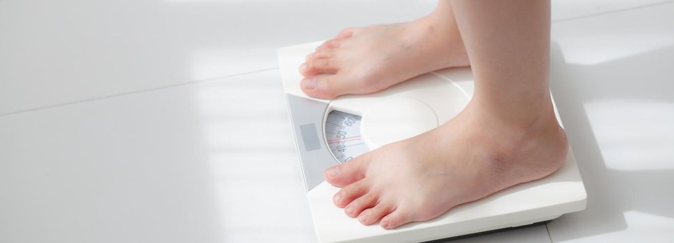 Lifestyle activity with leg of woman stand measuring weight scale for diet with barefoot, closeup foot of girl slim weight loss measure for food control, healthy care concept, banner website.