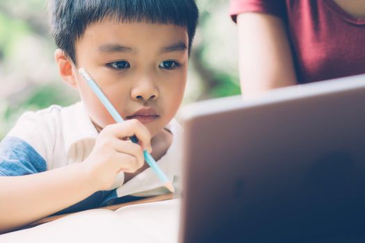 Son using digital tablet computer for study and learn to internet online with mother together, education from home, family recreation, mom teach boy and homework with technology, lifestyle concept.