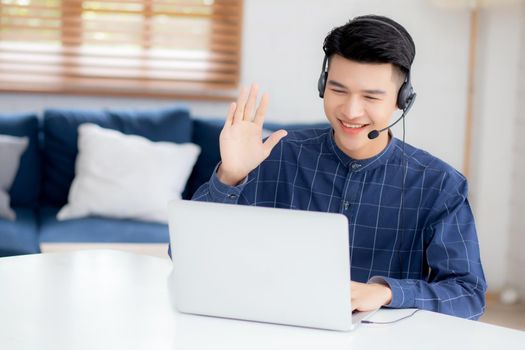 Young asian businessman working on laptop computer wearing headphone at home, business man wearing headset for video conference, communication and education, male study and learning for e-learning.