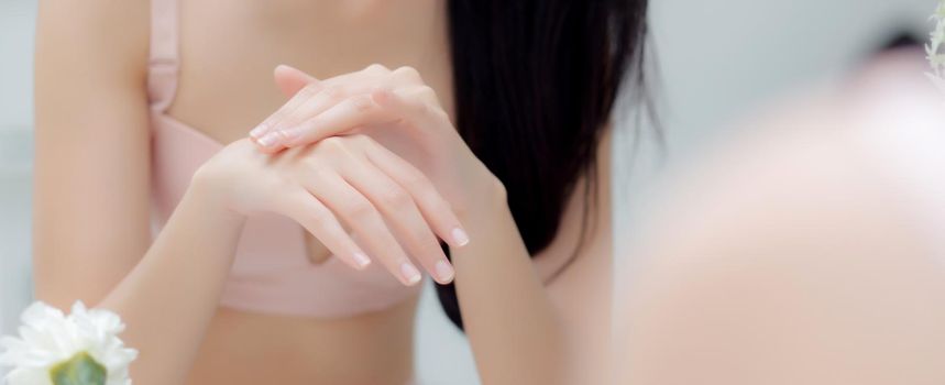 Closeup hand of young woman looking mirror applying cream on hand and message, beauty girl applying body lotion skin care for health, treatment and cosmetic with moisturizer, banner website.