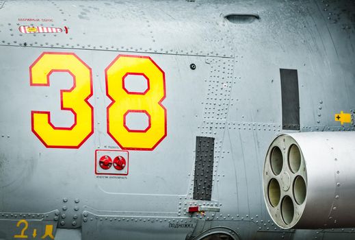 Side of helicopter with red and yellow drawn number 38 and text with russian letters on it. Close-up of military air transport with missile. Army chopper with rockets. Air forces of Russia.