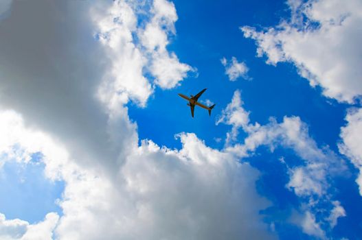 Passenger plane in the blue cloudy sky, summer time