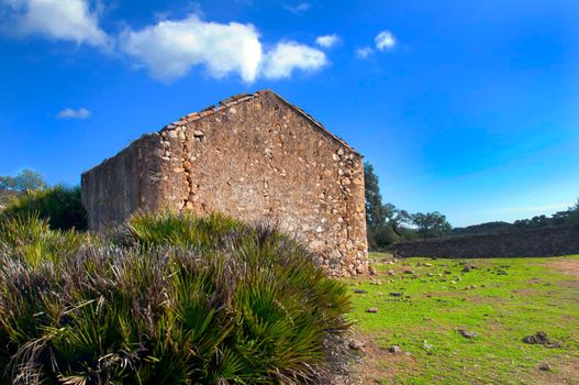 Abandoned stone house, green valley and blue sky with clouds. Sunny autumn day, Seville, Spain 