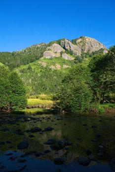 Peaceful place by the river in Argentinian Patagonia, overlooked by an imposing rocky mountain.