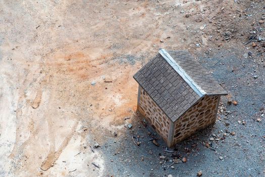 A small brown brick building with tiled roof on dry dirt surrounded by rocks