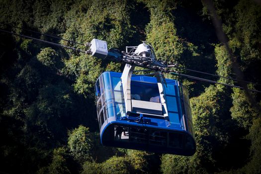 A small cable car travelling amongst trees in a forest on a mountain