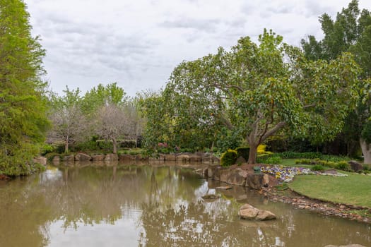 A small pond in a large garden surrounded by trees and flowers