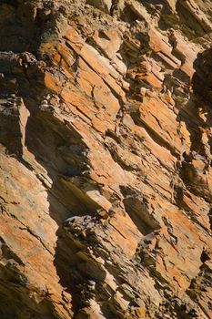 Reddish layered rock wall, with visible geological strata in the Andes mountains.