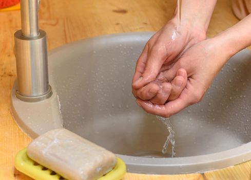 The girl's hands wash their hands in the sink, soap is in the foreground