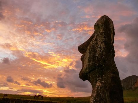 Statues of Easter Island in the background of the sunset. The melting of the Easter statue in the sunlight of the sunset.