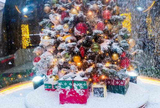 A Christmas tree with gifts underneath, covered with freshly fallen snow.