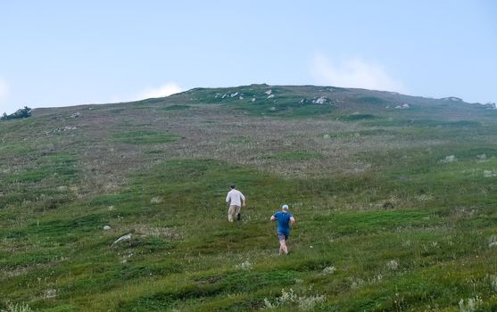 Two young men run up a high hill.