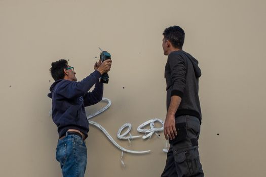 April 22, 2019, Limassol, Cyprus. Two workers are installing a cafe sign on a street in the city of Limassol.