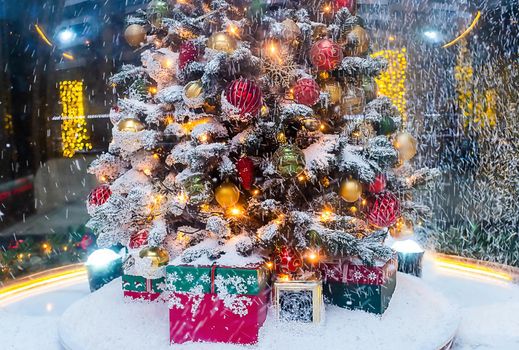 A Christmas tree with gifts underneath, covered with freshly fallen snow.
