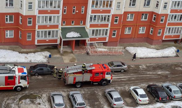 Fire engine in the courtyard of a multi-storey residential building in winter.