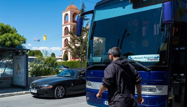 April 22, 2019, Limassol, Cyprus. Blue bus on the background of the bell tower of the Christian Church at the Limassol bus station