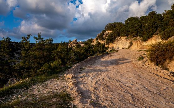 Sandy mountain road of the island of Cyprus in the light of the setting sun.