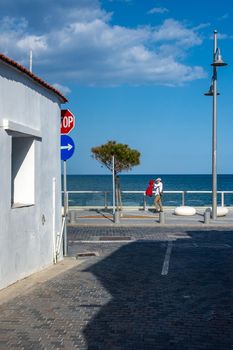 April 11, 2019, Larnaca, Cyprus. A man with a red jacket in his hands walks along the embankment on a Sunny day.