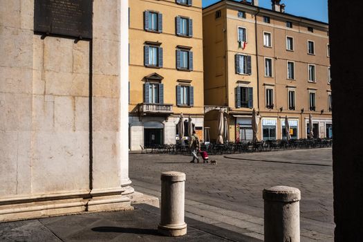 Rear view of a man pulling a shopping cart and walking with his dog in the old town street of Brescia. A looking of Italian life following restrictions on people's mobility to contain Coronavirus infection.