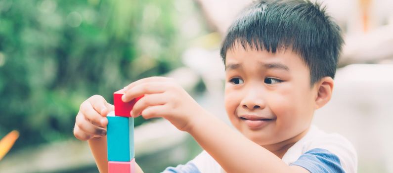 Asian young boy playing wooden block toy on table for creative and development, happy child learn skill for activity puzzle and creativity for game on desk at home, education concept, banner website.