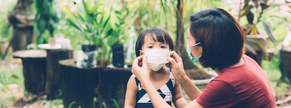 Mother take care daughter with face mask for protection disease flu or covid-19, mom wearing on medical mask with child safety for protect outbreak of pandemic, medical concept, banner website.