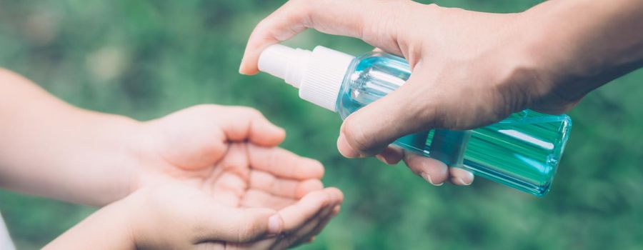 Mother take care daughter with sanitizer for protection disease flu or covid-19 outdoors, mom and child clean hand for safety for outbreak of pandemic in public, banner website.