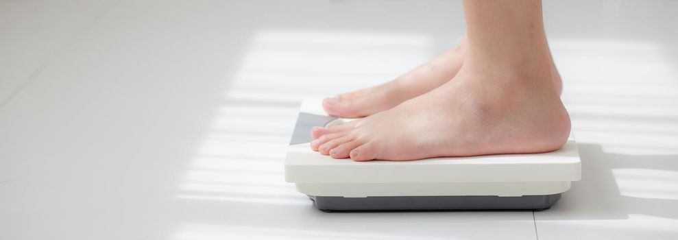 Activity with leg of woman stand measuring weight scale for diet with barefoot, closeup foot of girl slim weight loss measure for food control, healthy care and wellness concept, banner website.